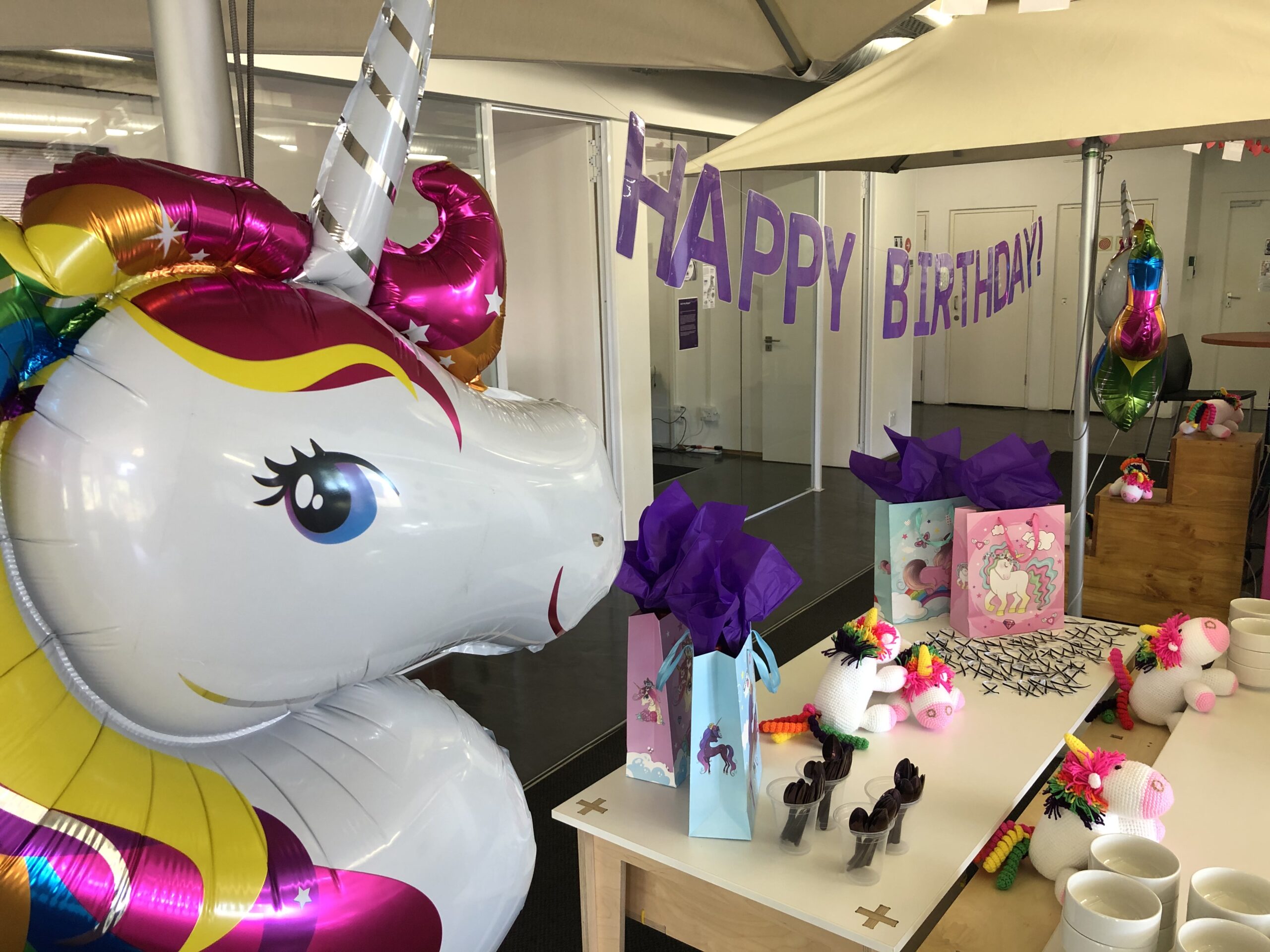 Skyler the unicorn next to a happy birthday sign and a table with goodies