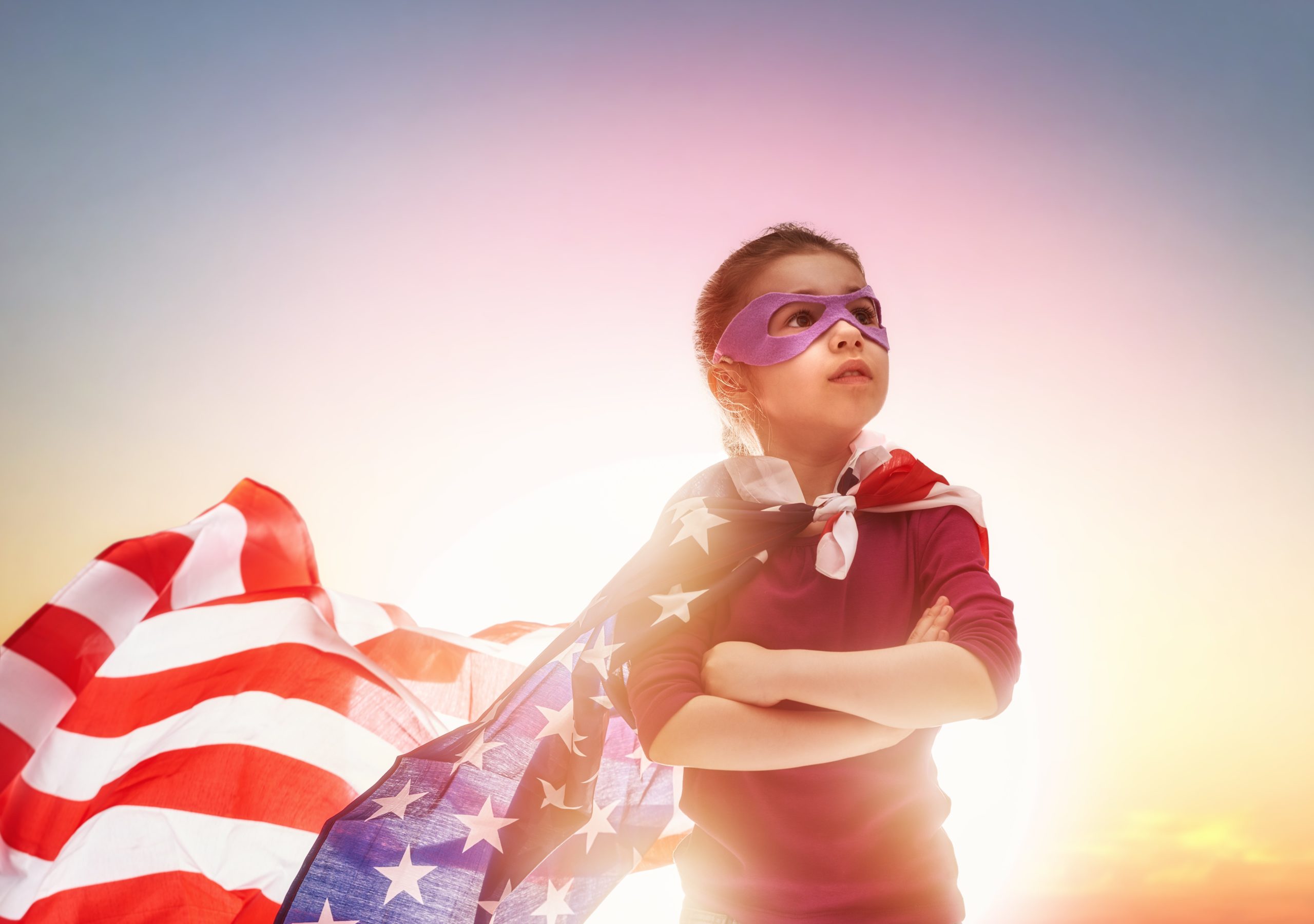 child dressed as American superhero with US flag as cape