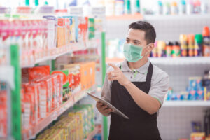 store clerk counting stock while wearing a face mask